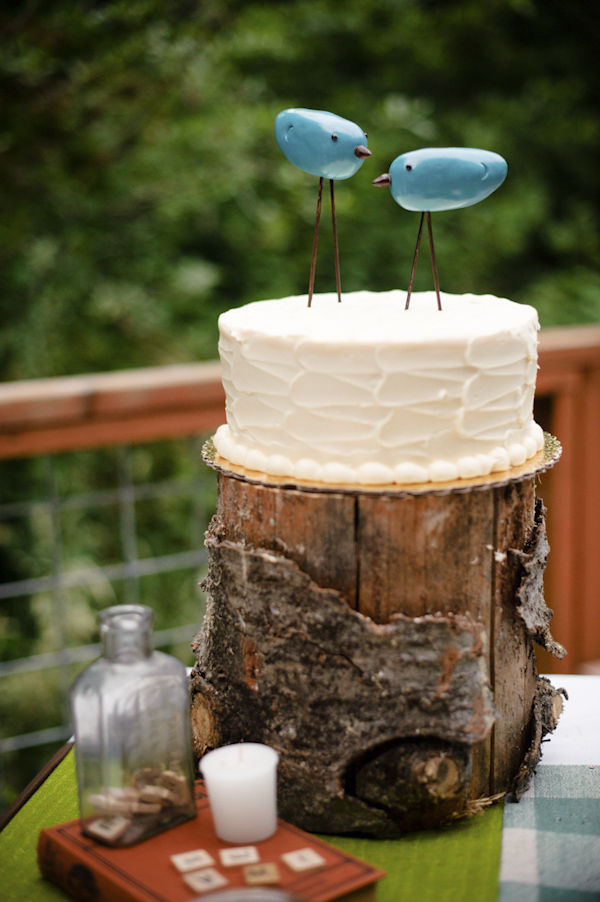 wedding cake with bird cake toppers and sitting on top of log- wedding photo by top Portland, Oregon wedding photographer Aaron Courter